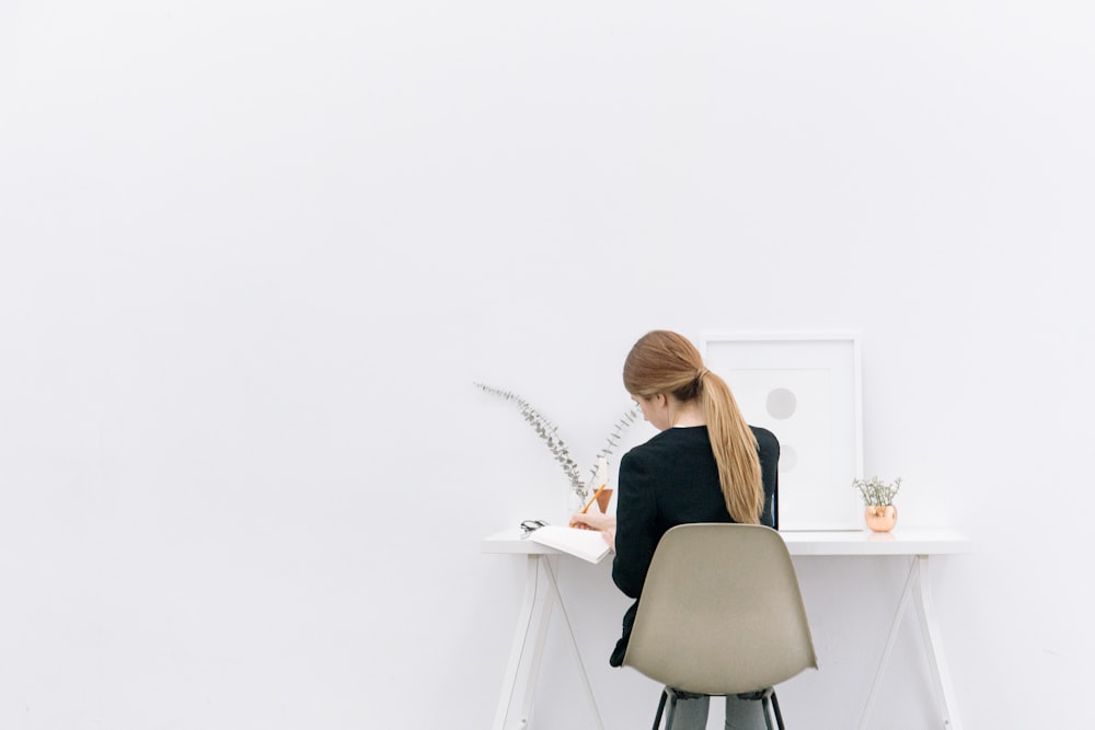 A long-haired woman sitting at a computer desk.