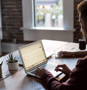 man operating laptop on top of table