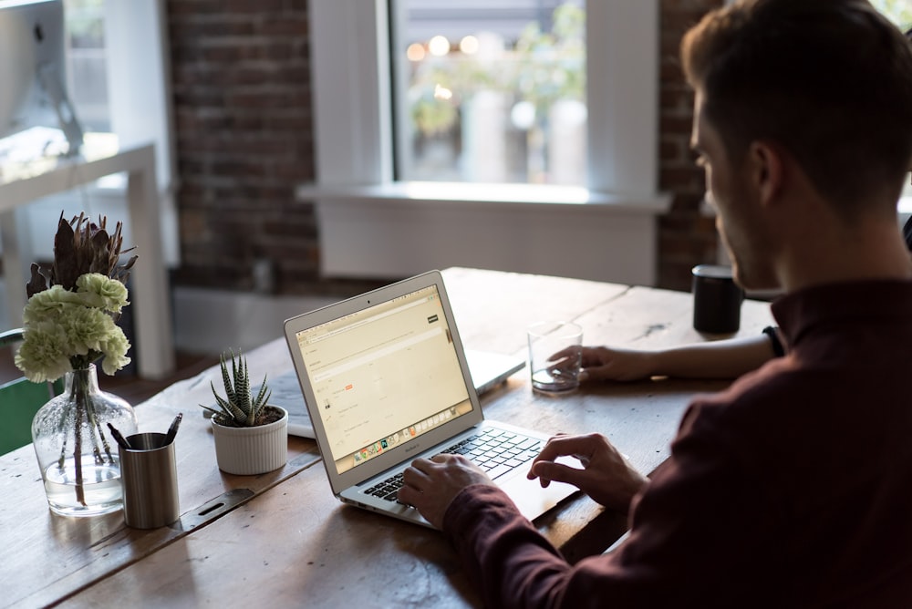 man operating laptop on top of table