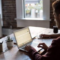 man operating laptop on top of table