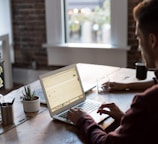 man operating laptop on top of table