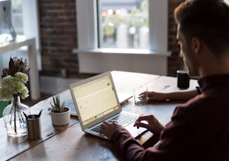 man operating laptop on top of table