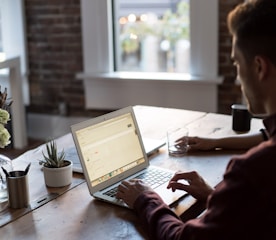 man operating laptop on top of table