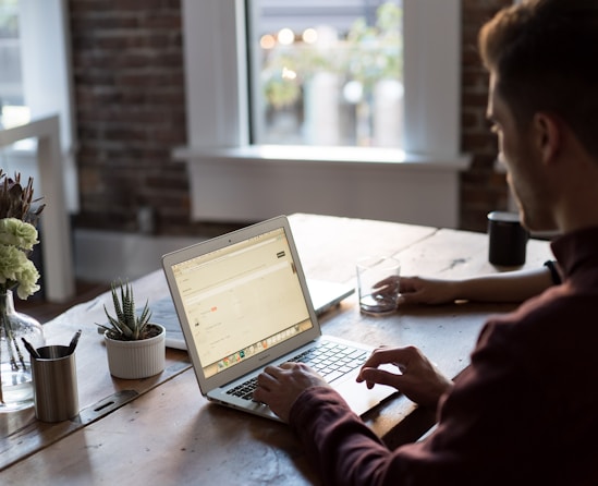 man operating laptop on top of table