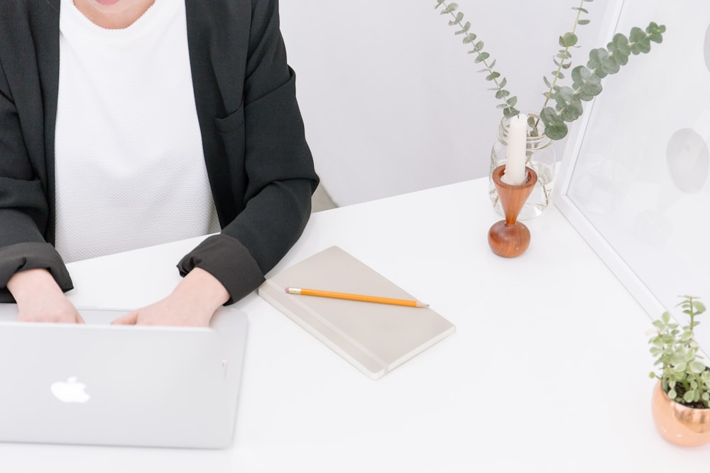 A person in business attire typing on a Macbook.