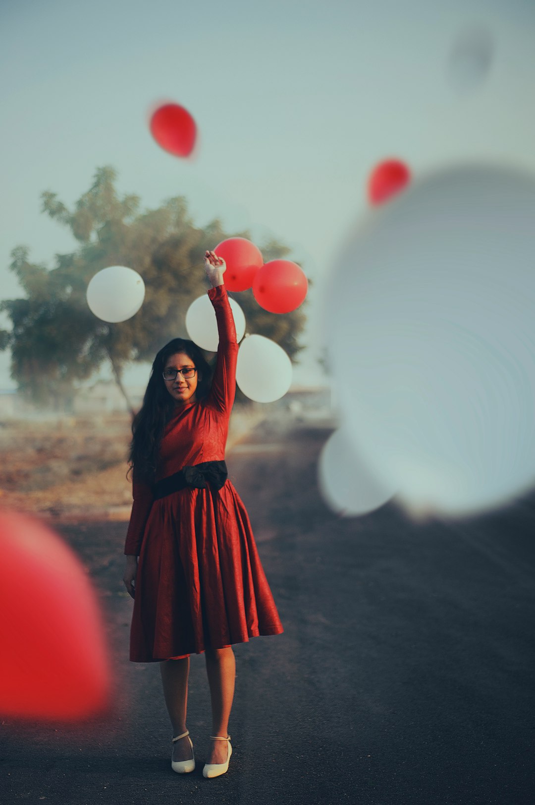 focus photography of woman standing on road raising her left hand