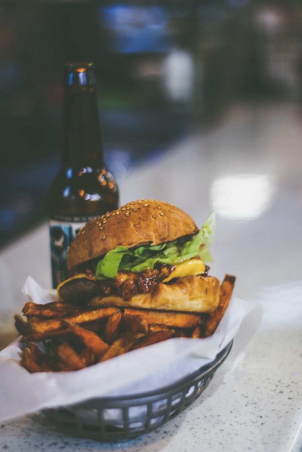 burger placed on grey bowl near beer bottle