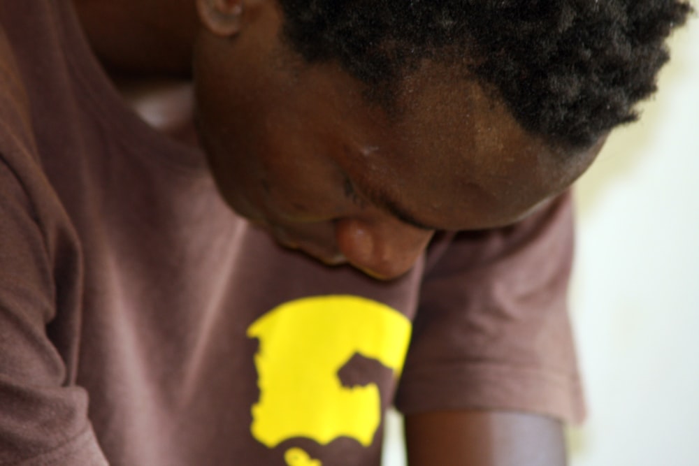 An African American man looking down at his hands while sitting for a prayer.