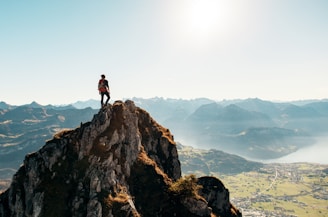 A vibrant photo of a happy traveler standing on a mountain peak overlooking a vast, colorful landscape.