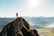 A hiker standing on a sunlit mountain peak overlooking a vast, glowing landscape.