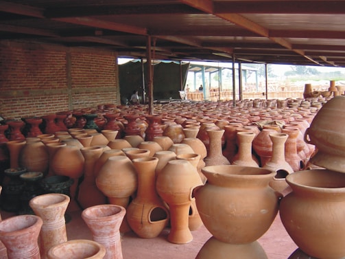 A collection of finished clay pots arranged on wooden shelves, showcasing various sizes and shapes.