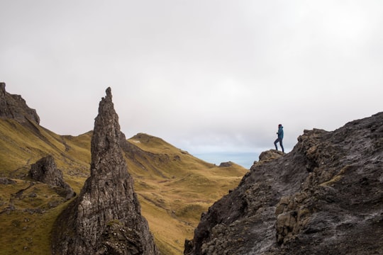 person standing on top of rock formation in The Storr United Kingdom