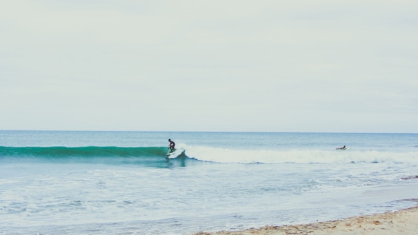 A beginner surfer catching a gentle wave on a sunny beach.