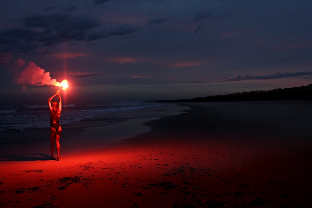 mulher em pé enquanto segura fogos de artifício