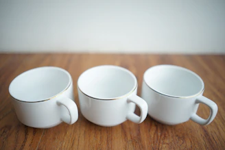 A row of matte black ceramic cups with sharp edges arranged on a white surface.