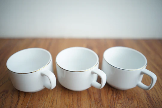 A row of matte black ceramic cups with sharp edges arranged on a white surface.