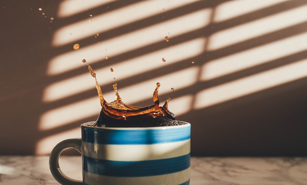 Tazza in ceramica a righe bianche e blu vicino al muro dipinto di bianco