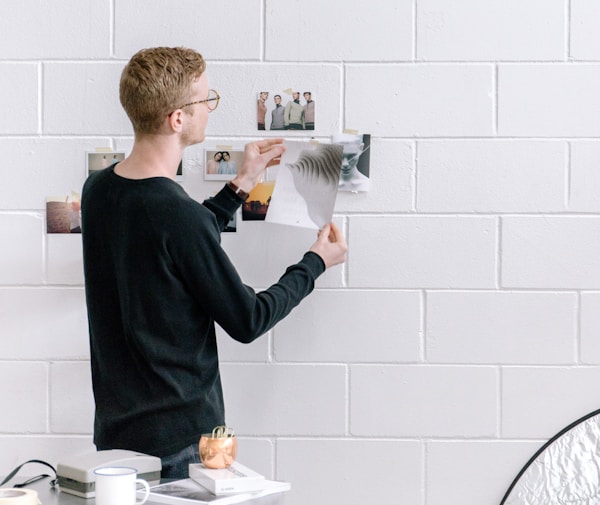 man holding paper infront by wall