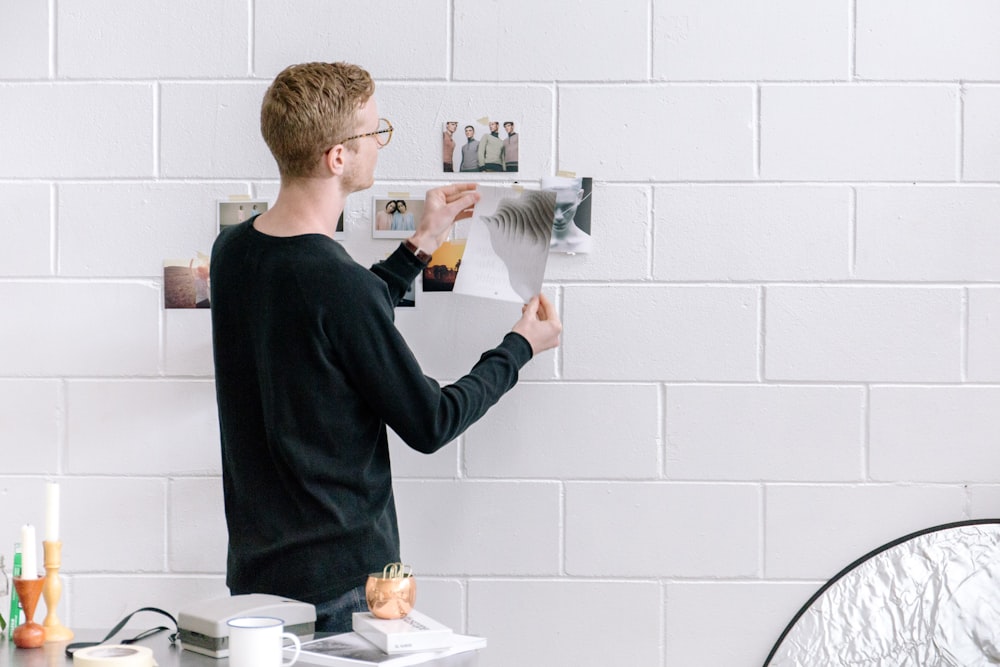 man holding paper infront by wall