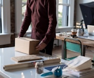 person holding cardboard box on table