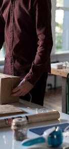 person holding cardboard box on table