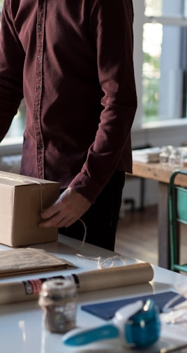 person holding cardboard box on table