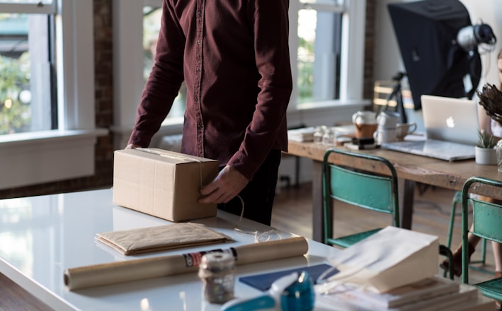 person holding cardboard box on table