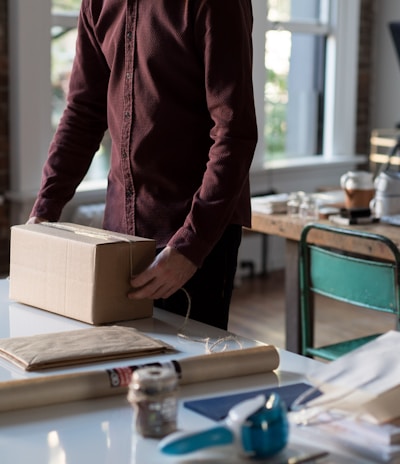 person holding cardboard box on table