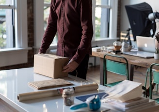 person holding cardboard box on table