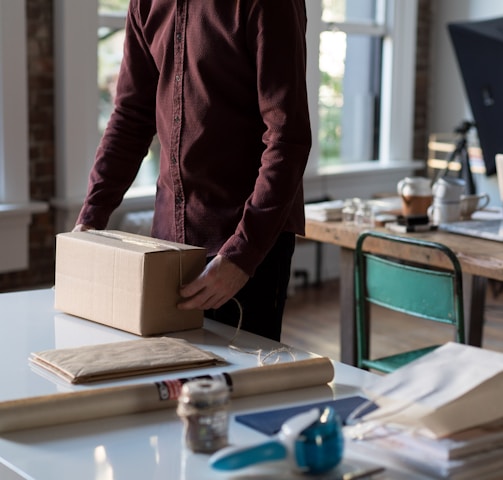 person holding cardboard box on table