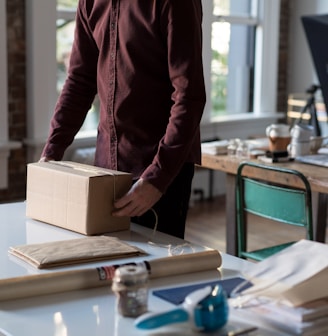 person holding cardboard box on table