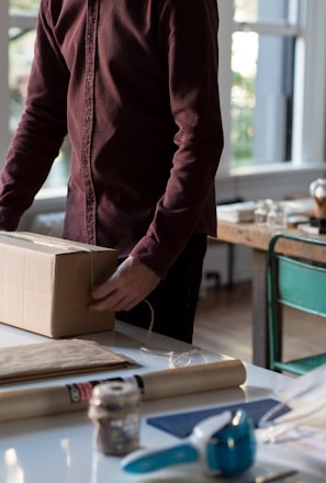 person holding cardboard box on table