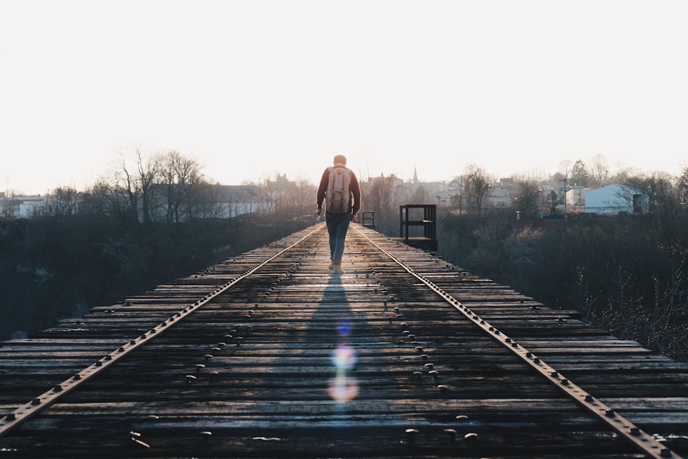 man walking in the middle of rail road