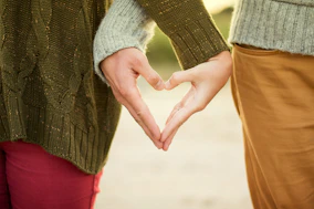 person forming heart shape with their hands