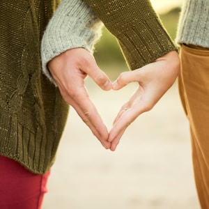 person forming heart shape with their hands