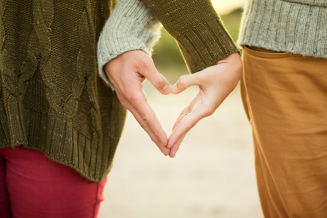 Close-up of couple's hands intertwined to create a heart shape