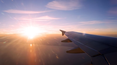 A vibrant sunrise viewed from an airplane window, with clouds glowing orange.