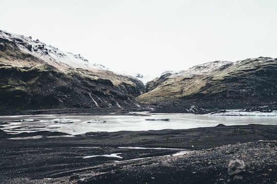 lake viewing mountain during daytime in Sólheimajökull Iceland