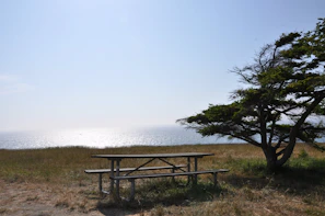 A picnic table with travel gear and a map laid out under a bright blue sky