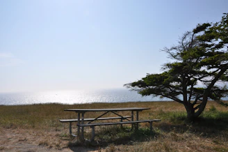 A picnic table with travel gear and a map laid out under a bright blue sky