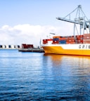 white and orange cargo ship with metal lifting equipment