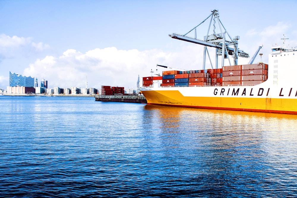 white and orange cargo ship with metal lifting equipment