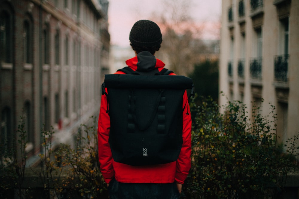 man with backpack standing in front of plant