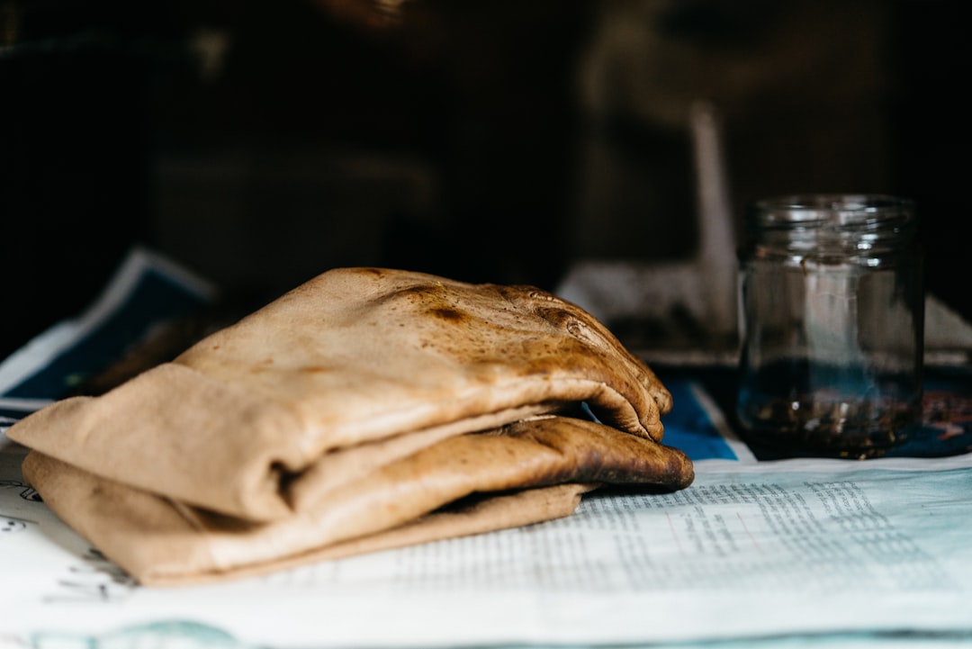 pair of brown leather gloves beside glass jar on newspaper