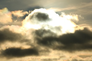 A dark, cloudy sky gradually brightening as if seen through a lens of light.