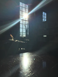 Portrait of a thoughtful writer sitting by a window with soft natural light, reflecting quietly.