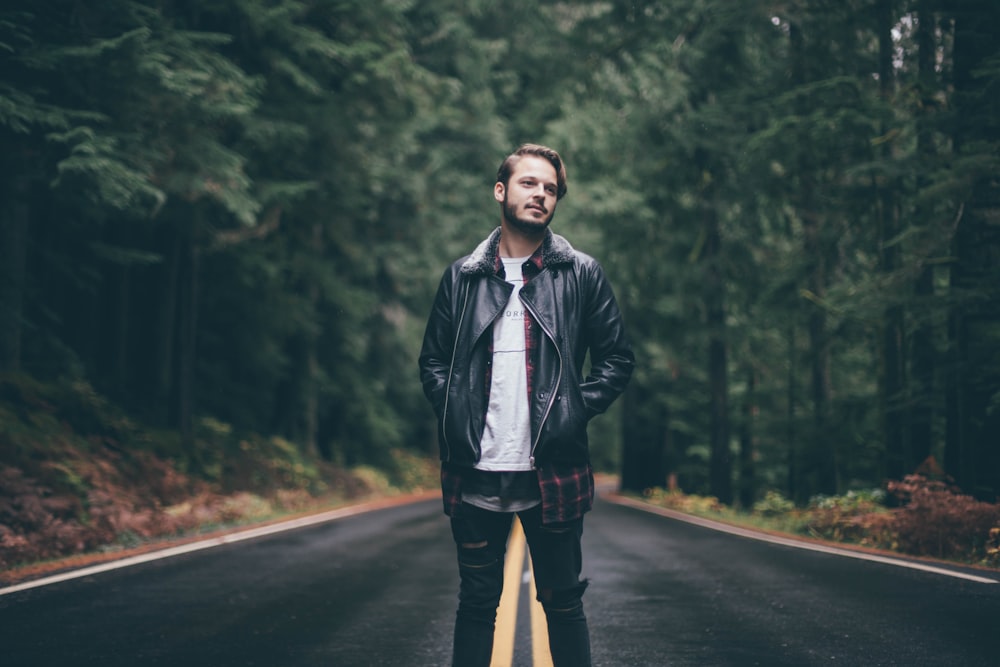 man wearing black zip-up jacket standing in middle of road