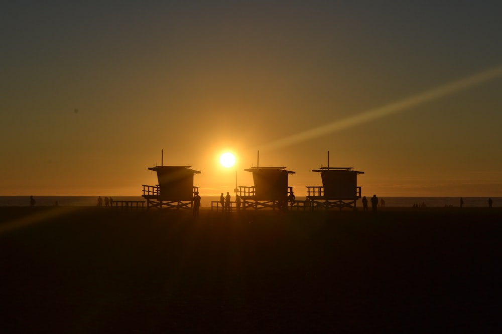 silhouette of three cottages on the beach