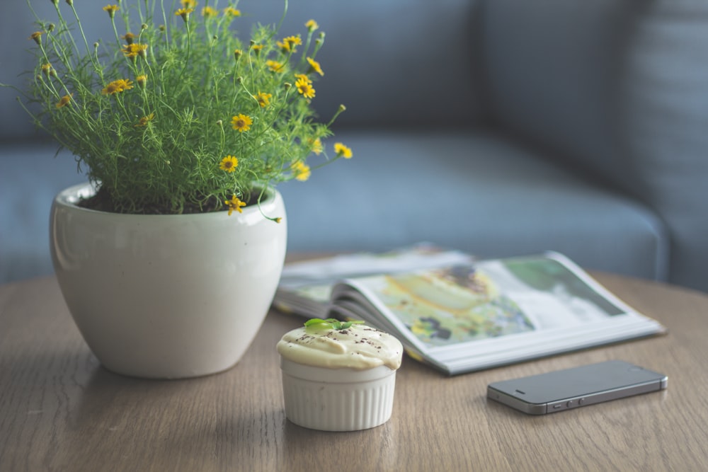 本とiPhone 5sのそばに黄色い花びらの花を植える