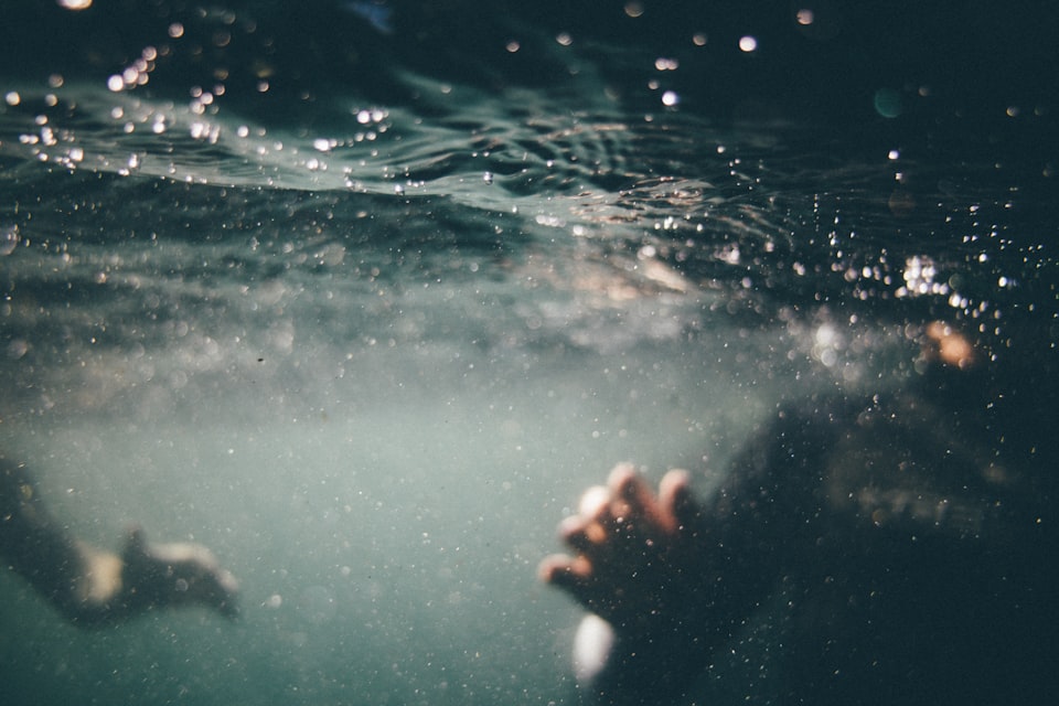 Blurry underwater photo showing a person's hand reaching towards the camera